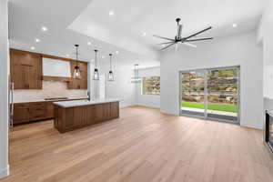 Kitchen featuring open floor plan, gas cooktop, light countertops, custom exhaust hood, and ceiling fan