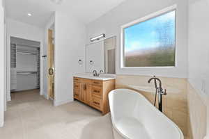 Full bathroom featuring a stall shower, a walk in closet, vanity, and a soaking tub