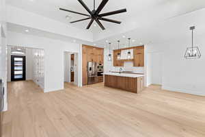 Kitchen with stainless steel fridge with ice dispenser, custom range hood, a chandelier, open floor plan, and light countertops