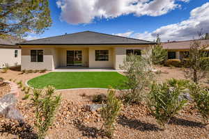 Rear view of property featuring stucco siding, a lawn, and a patio area