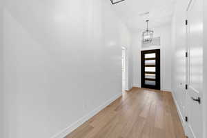 Foyer with light wood-style floors, baseboards, and a chandelier