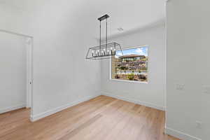 Unfurnished dining area with baseboards, light wood finished floors, and a chandelier