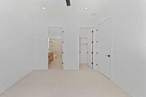 Unfurnished bedroom with a walk in closet, light carpet, recessed lighting, baseboards, and ensuite bath