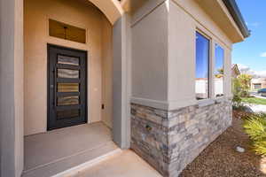 Doorway to property featuring stone siding and stucco siding