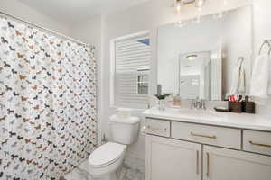 Bathroom featuring marble finish floors, toilet, vanity, a shower with shower curtain, and baseboards