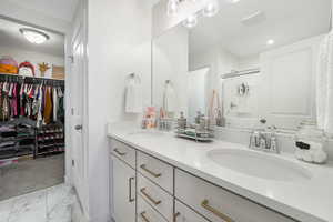 Full bathroom with a shower stall, marble finish flooring, double vanity, and a spacious closet