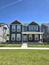 View of front of house with board and batten siding, a porch, and a front lawn