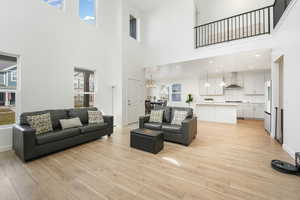 Living area with a towering ceiling, light wood-style floors, and baseboards