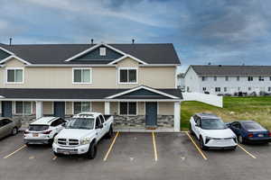 View of front of house featuring roof with shingles, stone siding, and uncovered parking