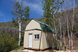 View of 12.5' x 16.5' shed featuring a forest view