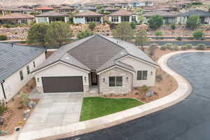 View of front of home with stucco siding, stone siding, a garage, and a residential view