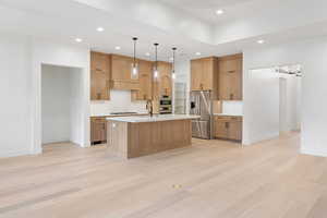 Kitchen with appliances with stainless steel finishes, recessed lighting, light countertops, decorative backsplash, and light wood-type flooring