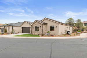 Ranch-style house featuring stucco siding, stone siding, driveway, and an attached garage
