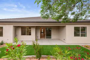 Back of house featuring stucco siding, a lawn, and a patio area