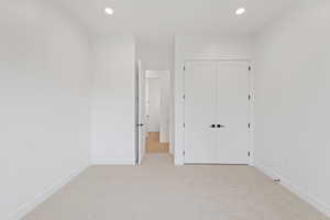 Unfurnished bedroom with light colored carpet, baseboards, a closet, and recessed lighting