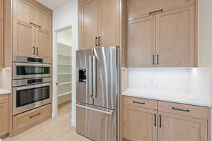 Kitchen with appliances with stainless steel finishes, decorative backsplash, light wood-style flooring, and light brown cabinets