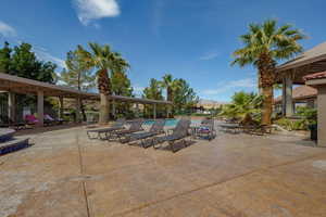 View of patio with a community pool and fence