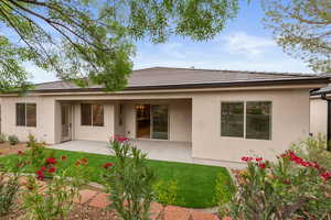 Back of property with a lawn, stucco siding, and a patio area
