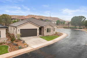 Single story home featuring stone siding, stucco siding, a tile roof, concrete driveway, and an attached garage