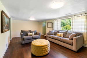 Living room with baseboards, dark wood finished floors, and a textured ceiling