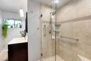 Bathroom with a shower stall, vanity, tile patterned flooring, and baseboards