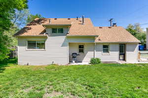 Rear view of house with roof with shingles and a chimney