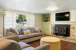 Living area featuring wood finished floors, a textured ceiling, a fireplace, and built in shelves