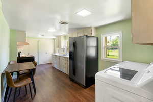 Kitchen with stainless steel fridge with ice dispenser, a sink, light countertops, dark wood-style flooring, and independent washer and dryer