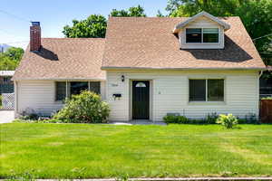 Cape cod-style house featuring a shingled roof and a chimney