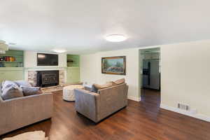 Living area with dark wood-style floors, baseboards, and a fireplace