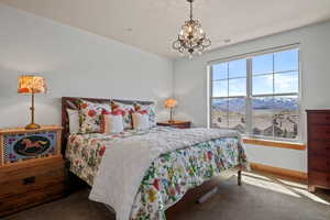 Carpeted bedroom featuring a mountain view, visible vents, baseboards, and a notable chandelier