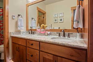 Full bathroom featuring toilet, double vanity, and a sink