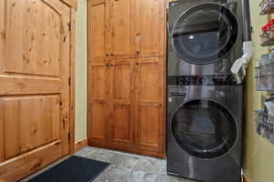 Laundry area featuring cabinet space, baseboards, and stacked washer and dryer