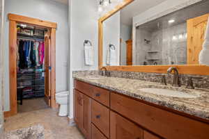 Bathroom with double vanity, toilet, a tile shower, and a sink