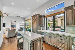 Kitchen featuring decorative backsplash, recessed lighting, open floor plan, light stone countertops, and a breakfast bar area