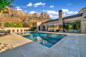 View of swimming pool featuring a pool with connected hot tub, a patio area, a mountain view, and outdoor lounge area