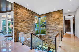 Hallway with an upstairs landing, light tile patterned floors, and recessed lighting