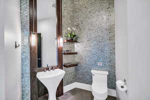 Half bath featuring tile patterned floors and tile walls