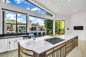Kitchen featuring recessed lighting, light tile patterned floors, stainless steel gas cooktop, a kitchen island, and white cabinets