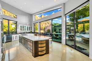 Kitchen with appliances with stainless steel finishes, recessed lighting, glass insert cabinets, a high ceiling, and light tile patterned flooring