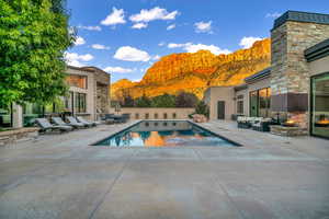 View of pool with a mountain view, a patio, an outdoor living space with a fireplace, and a jacuzzi