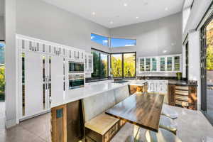 Kitchen with glass insert cabinets, a towering ceiling, a kitchen island, recessed lighting, and oven