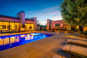 Pool at dusk featuring a patio area, outdoor lounge area, and a pool with connected hot tub