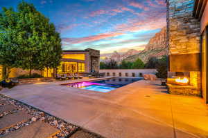 View of swimming pool with a patio, an outdoor living space with a fireplace, and an in-ground hot tub