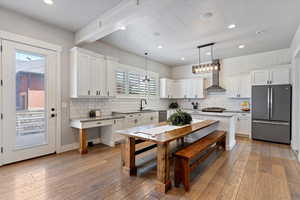 Open-concept kitchen and dining area featuring granite countertops, a gas stovetop range with hood, and a stylish tiled backsplash. The space includes a large farmhouse-style table—ideal for everyday meals and entertaining