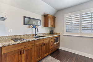 The kitchenette includes sleek cabinetry, a full-size fridge, microwave, stove top, and sink—ideal for quick meals and light cooking.