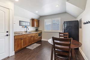 The kitchenette includes sleek cabinetry, a full-size fridge, microwave, stove top, and sink—ideal for quick meals and light cooking.