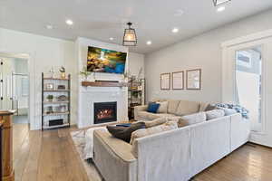 Spacious great room with soaring ceilings, warm wood-style flooring, and a cozy fireplace that creates the perfect gathering space.
