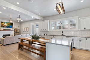 Spacious great room featuring warm wood-style flooring, recessed lighting, and a large farmhouse-style dining table—perfect for gatherings and entertaining