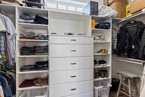 Expansive walk-in closet with built-in shelves and drawers, a window that brings in natural light, and ample hanging space for organized storage.